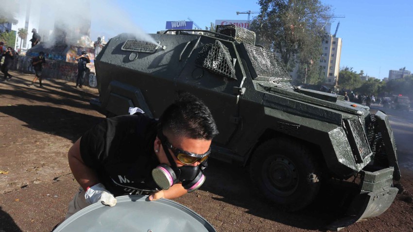 Un grupo de personas se enfrenta a la policía antidisturbios, este viernes, en la Plaza Italia en Santiago de Chile durante una nueva jornada de protestas.