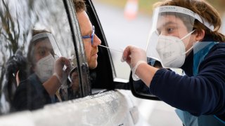A member of staff is reflected in the car window as Nick Markham, the founder of ExpressTest, takes a PCR swab test at Gatwick Airport on November 27, 2020 in London