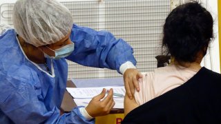 Enfermera pone una vacuna en el brazo a una paciente.