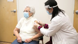 Farmacéutica administrando vacuna contra el coronavirus a una señora.