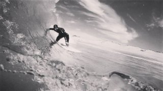 El surfista español Óscar Serra entre una enorme ola en una fotografía en blanco y negro