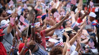 People in crowd waving tiny American flags.