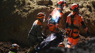 Rescatistas sacan uno de los dos cuerpos hallados en el interior del socavón en Villa, Nueva, Guatemala, el jueves en la noche.