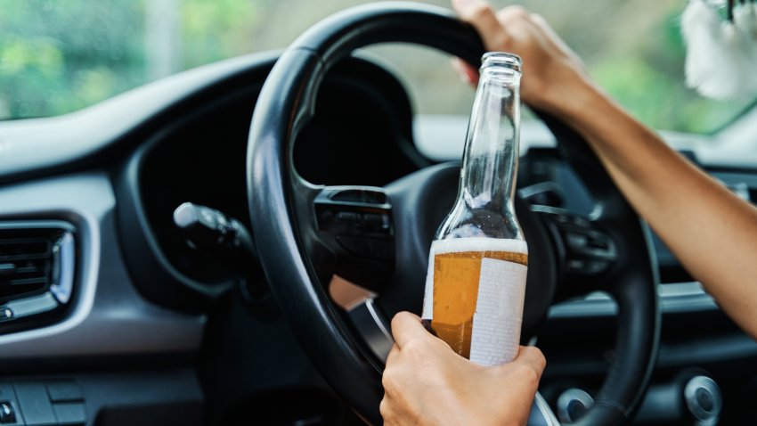 Young drunk woman drinking a beer while driving her car. Concept of alcohol abuse, addiction, alcoholism and dangerous driving.