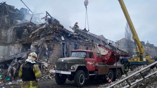 En esta imagen proporcionada por el Servicio Ucraniano de Emergencias, rescatistas trabajan en el lugar donde proyectiles dañaron un edificio en Novogrodivka, Ucrania, el jueves 30 de noviembre.