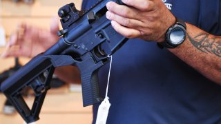 Un hombre muestra un acelerador de disparos instalado en un rifle AR-15.