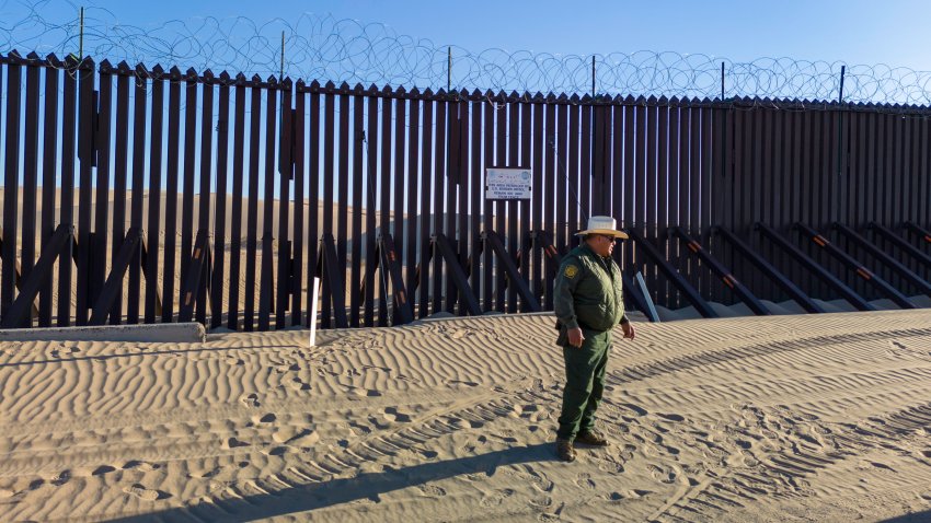 A U.S. Border Patrol agent stands near the border fence which stretches through the Imperial Sand Dunes on March 8, 2024 in Imperial County, California.