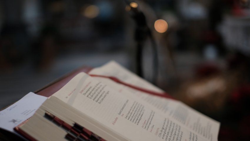 Bible or holy book in church seen in profile in dim light, with red bookmarks and dark background