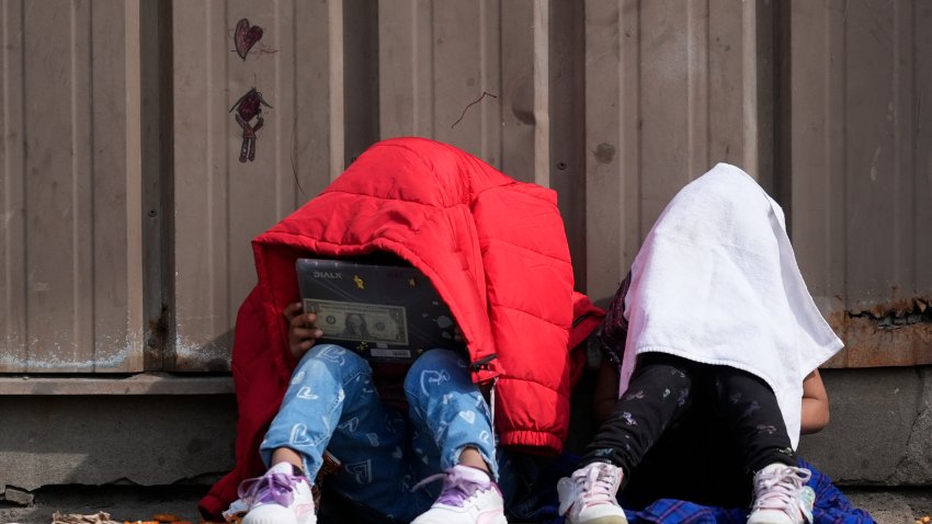 ARCHIVO – Dos niños se cubren la cabeza mientras permanecen afuera de un refugio para migrantes, el miércoles 13 de marzo de 2024, en el vecindario Pilsen de Chicago. (AP Foto/Erin Hooley, archivo)