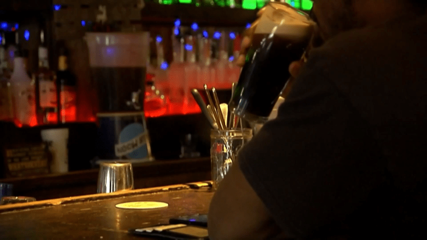 Man drinks beer at dark bar